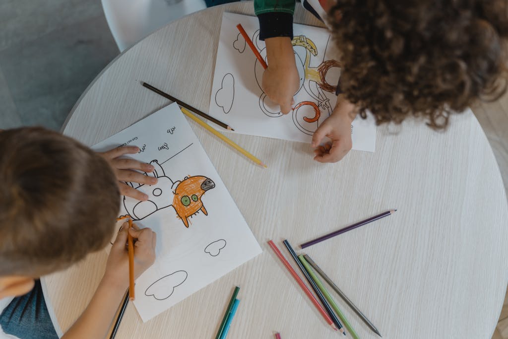 Two Kids Coloring a Drawing on White Paper